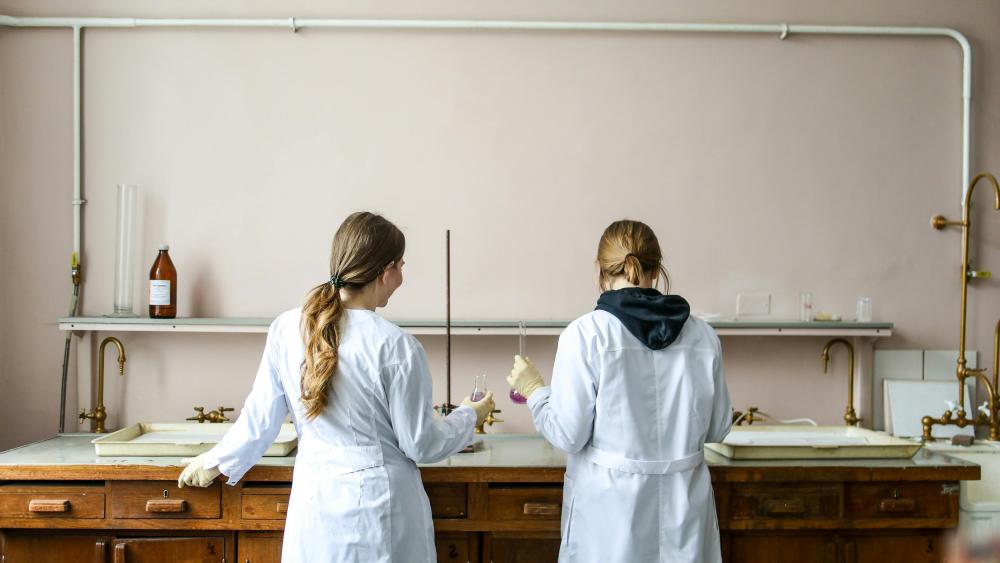 two students in lab coats in a laboratory