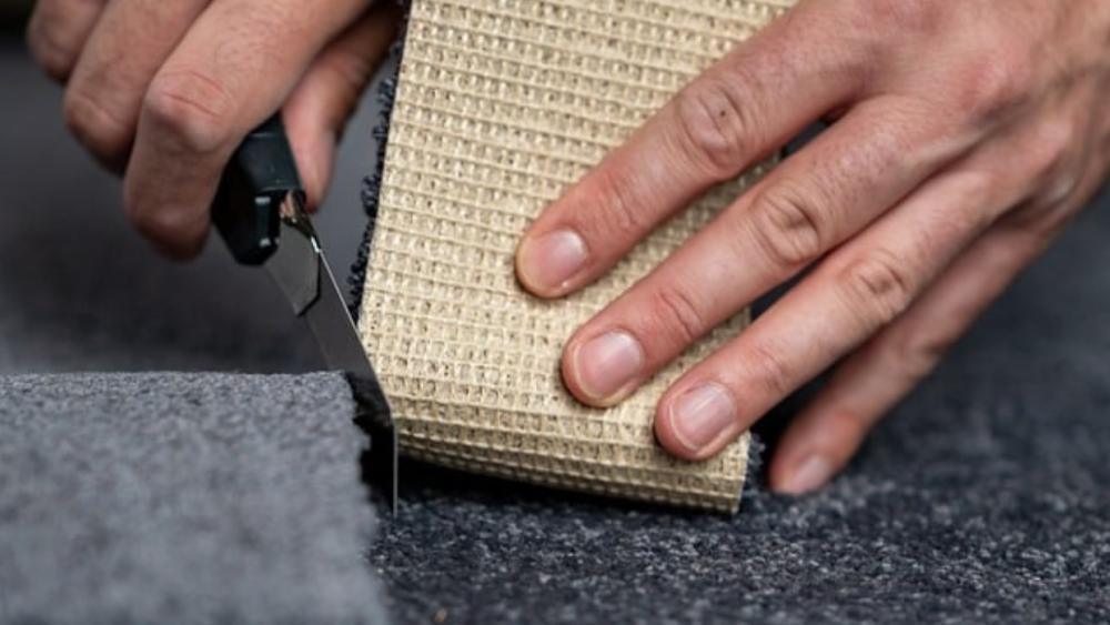 A person cuts carpet with a knife. 