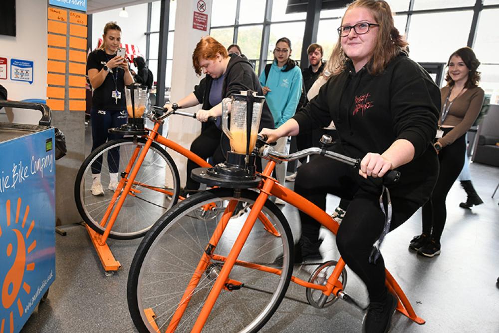 Students riding a stationary bike to blend a smoothie