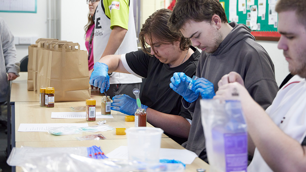 ILS students sat at tables wearing plastic gloves and measuring chilli powder