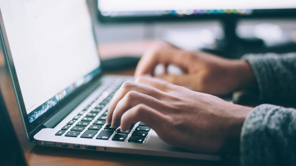 Close up of hands typing on a laptop keyboard