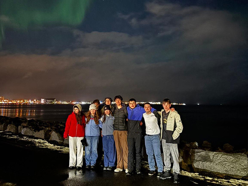 Group of students with the Northern Lights in the sky behind them