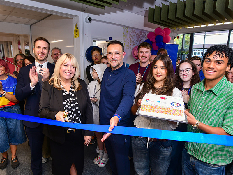 Group picture of staff and students cutting the ribbon and holding cake