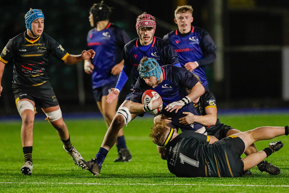 Student rugby players on the pitch mid-tackle