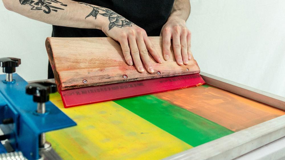 Squeegee pushing ink through when printmaking