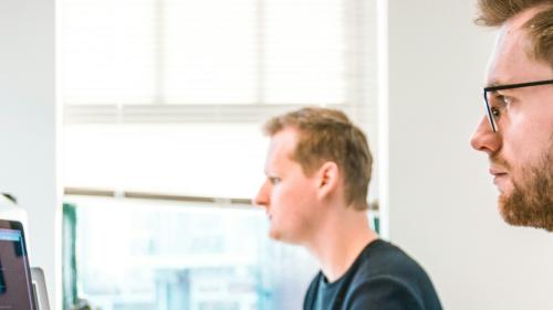 Two people review information on their computers in the office. 