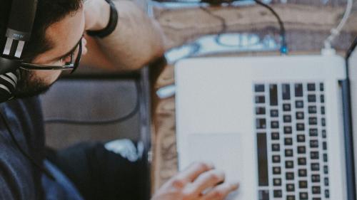 A person wearing headphones works on their laptop.