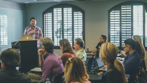 A tutor gives a presentation to a group of adult learners. 