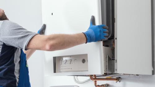 Person putting cover back on home boiler system