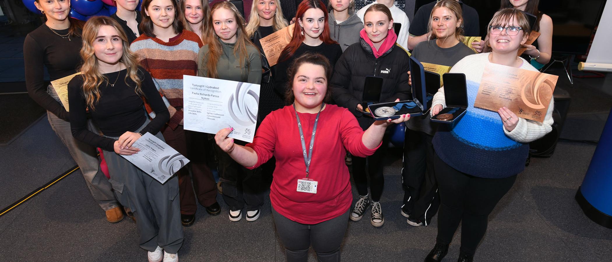 Students holding medals and certificates