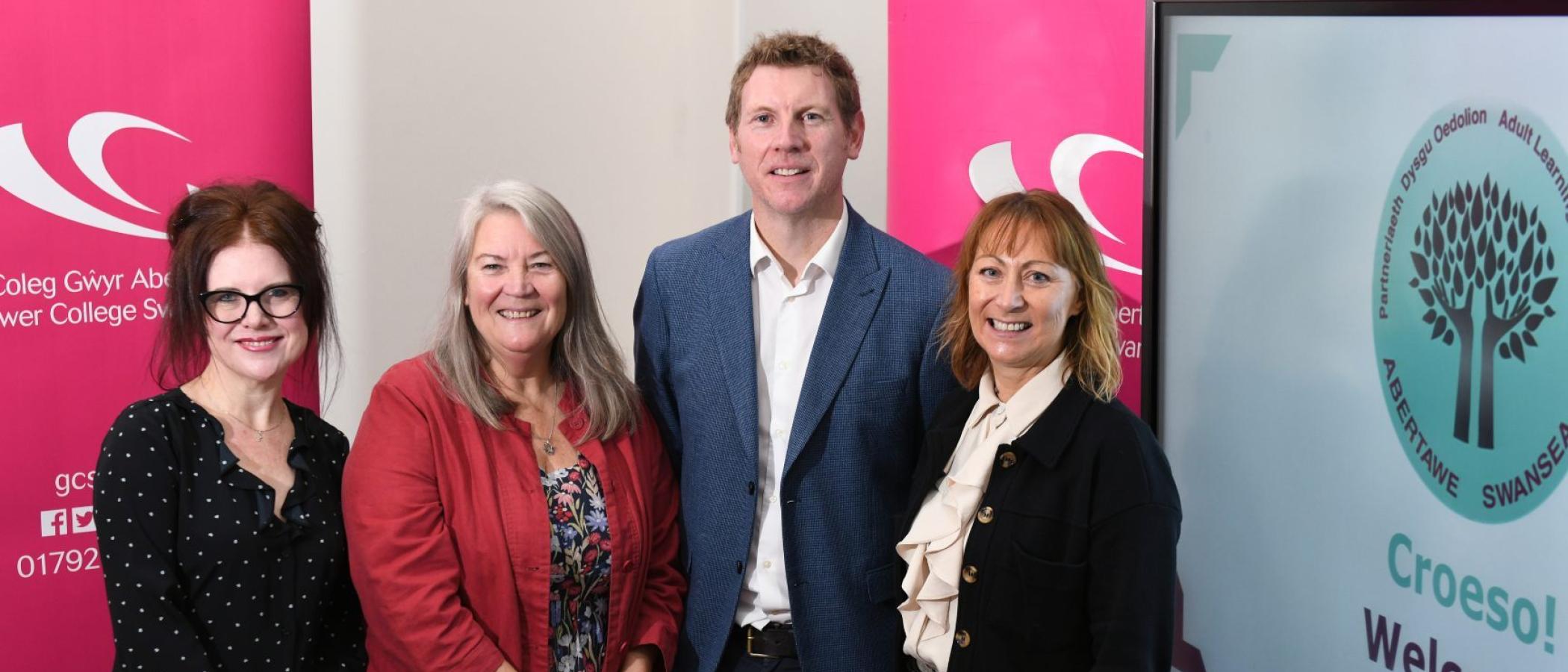 Four ALPS members standing in front of pink Gower College Swansea pull-up banners and the ALPS logo on screen with text saying Croeso! Welcome!