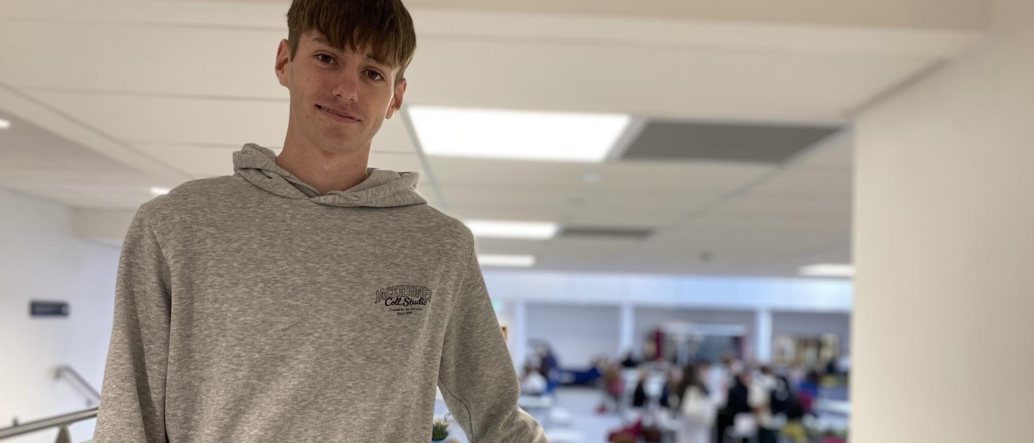 Student in grey hoodie standing in college area