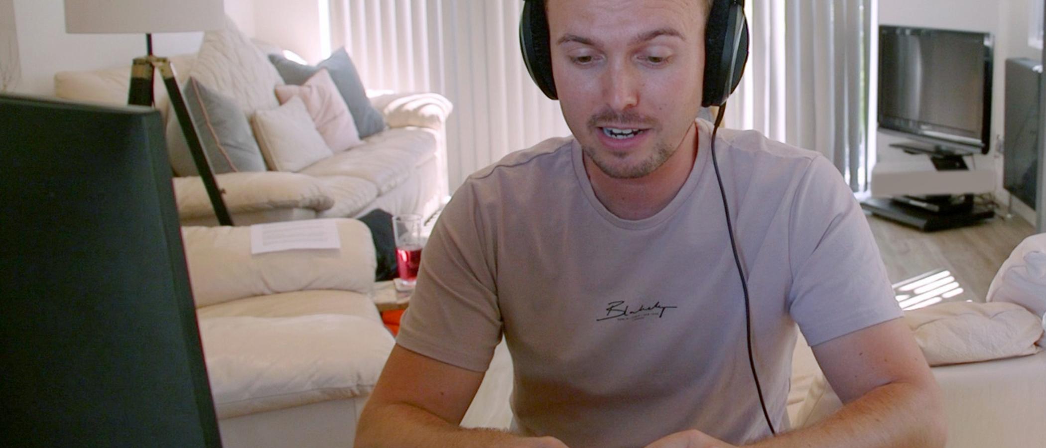 Dyn yn gweithio ar gyfrifiadur gyda chlustffonau / Man on PC with headphones