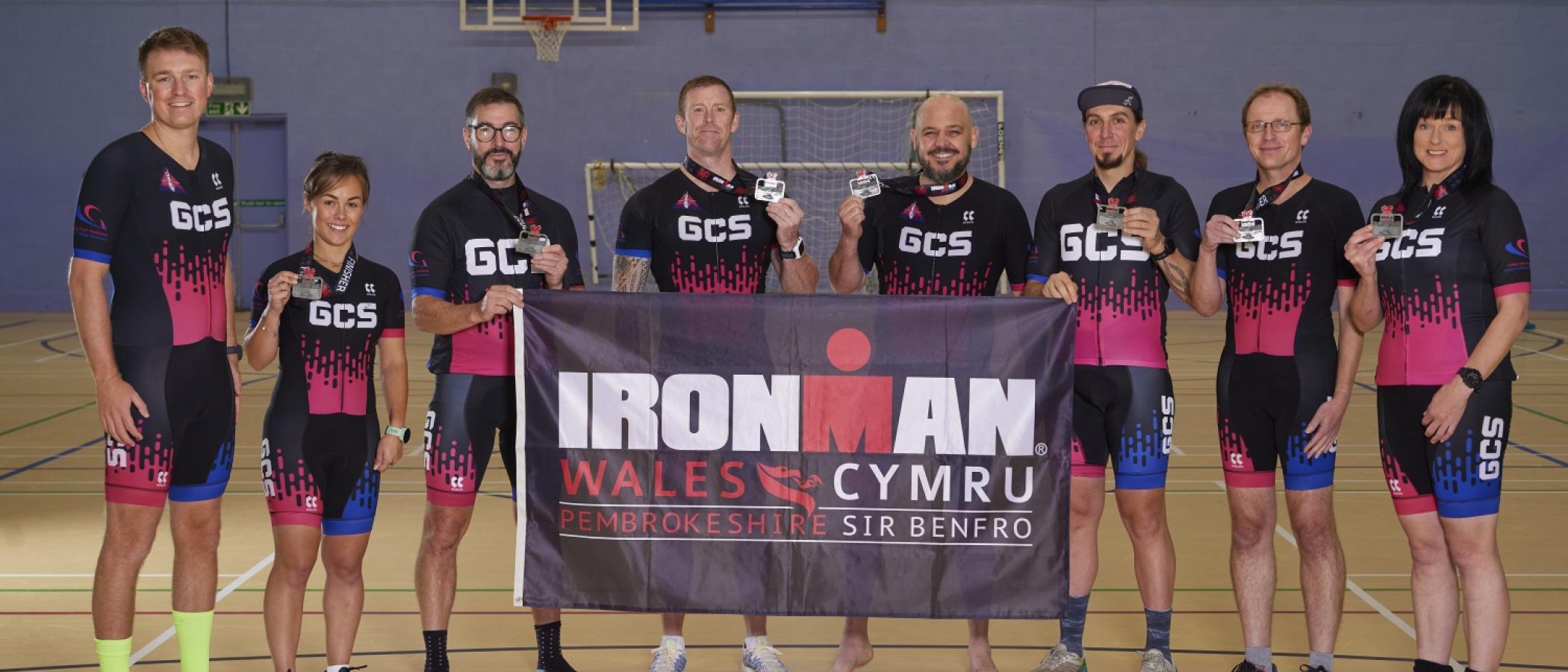 Group of people in sport kits, holding medals and flag
