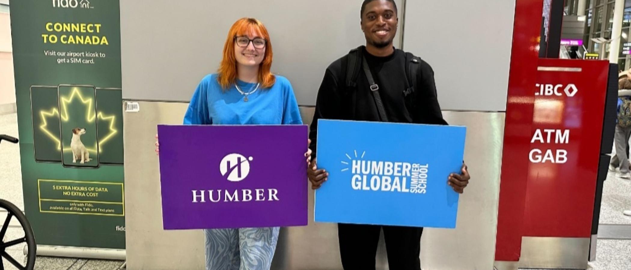 Two people holding Humber Global Summer School banners