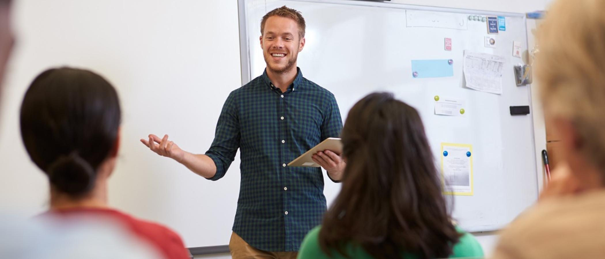  A male teacher standing in front of adult learners in a classroom