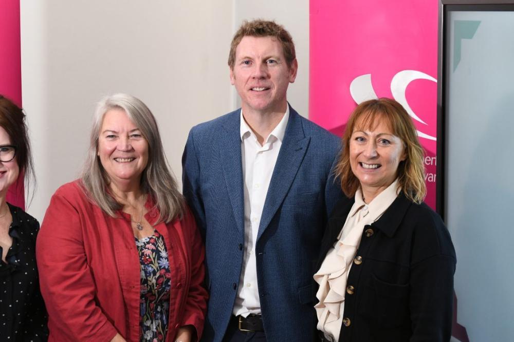Four ALPS members standing in front of pink Gower College Swansea pull-up banners and the ALPS logo on screen with text saying Croeso! Welcome!