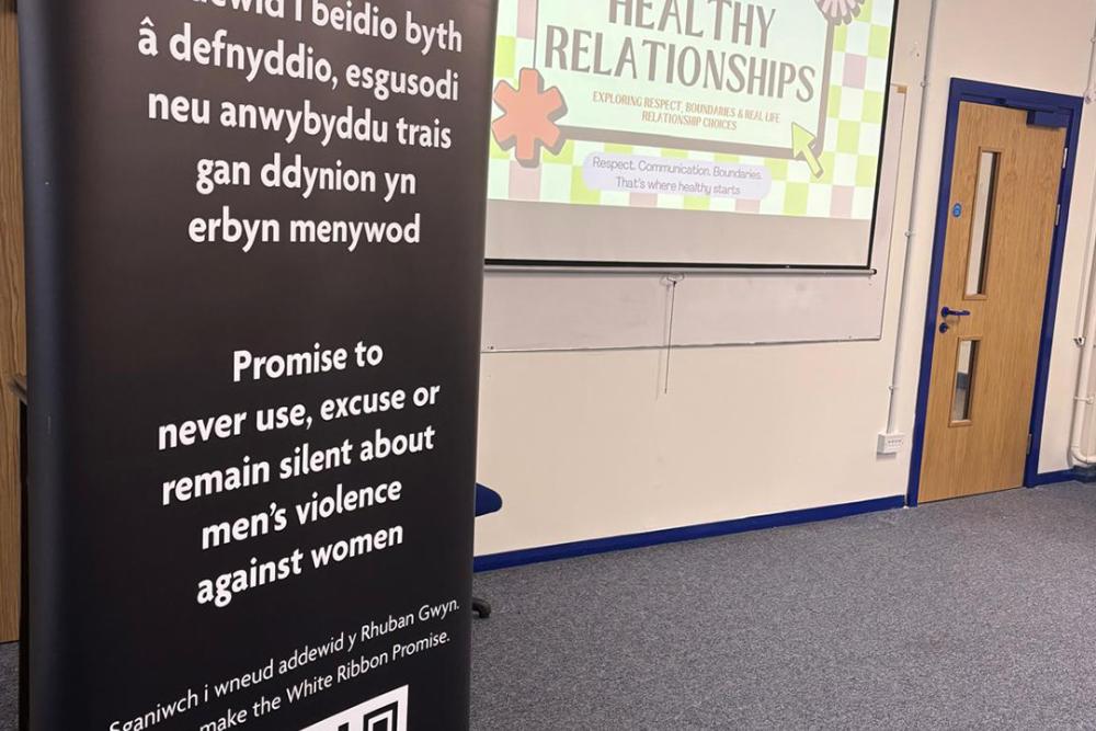 White Ribbon banner in front of screen with presentation for healthy relationships