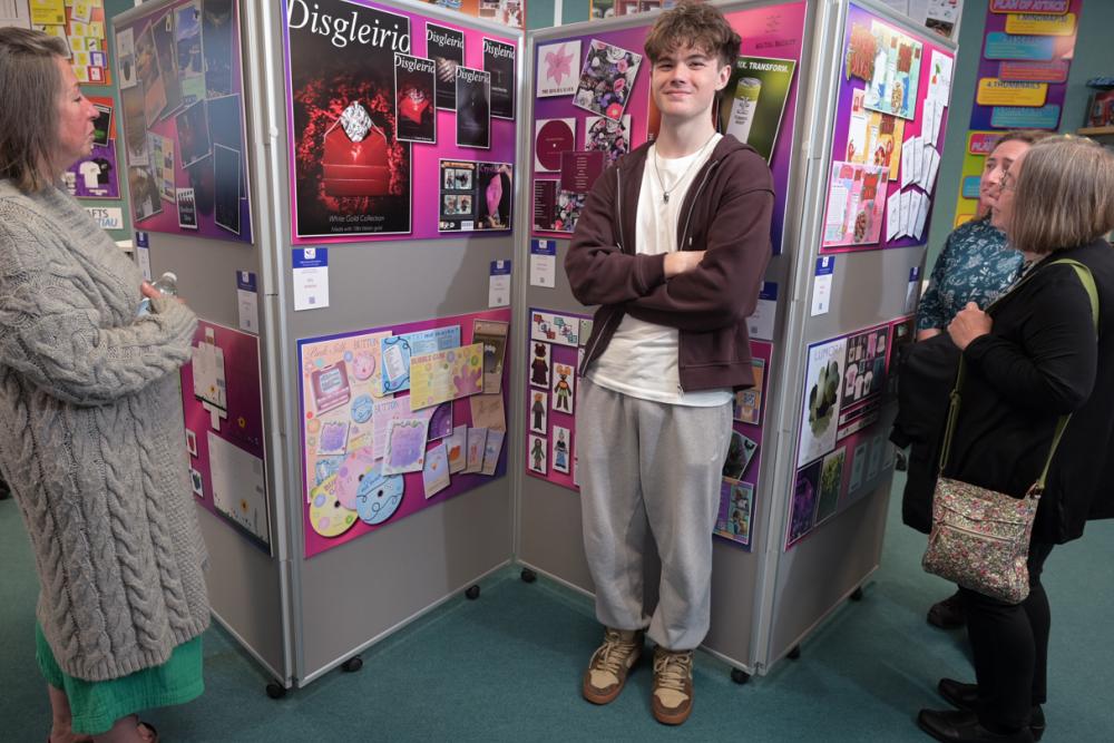 Elis Jenkins stands next to his graphic design work