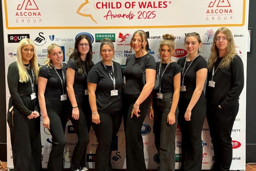 Group of eight young people at event, wearing black and smiling