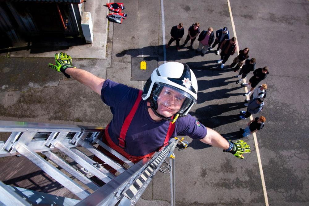 Firefighter on ladder with students in background
