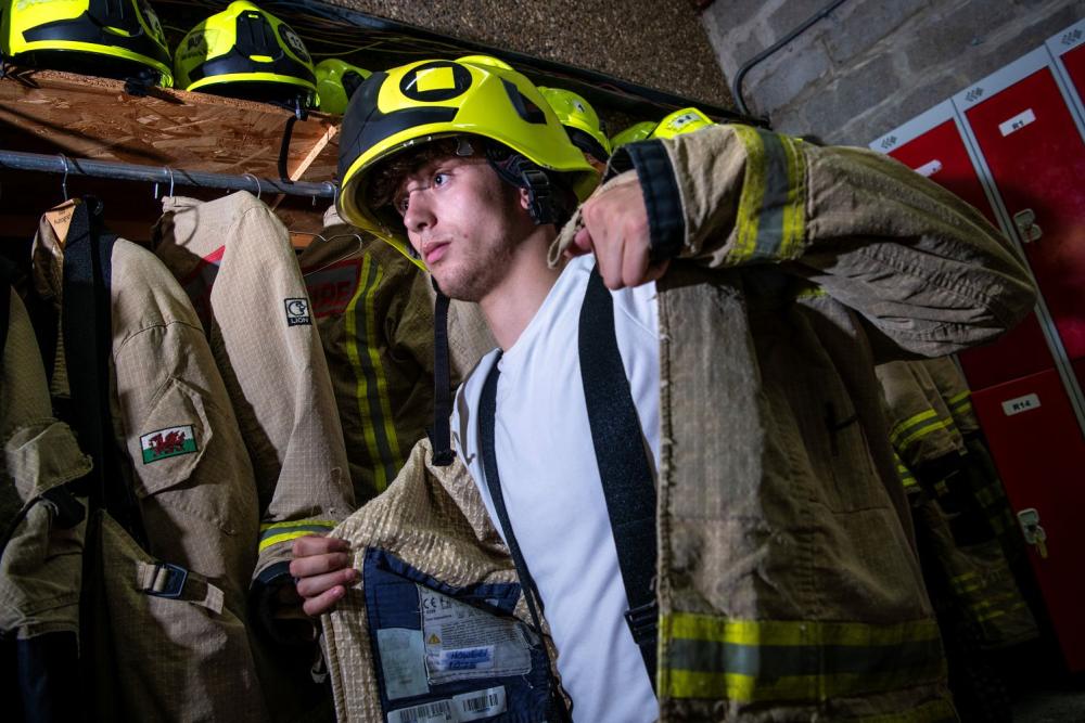 Student trying on firefighter jacket and helmet