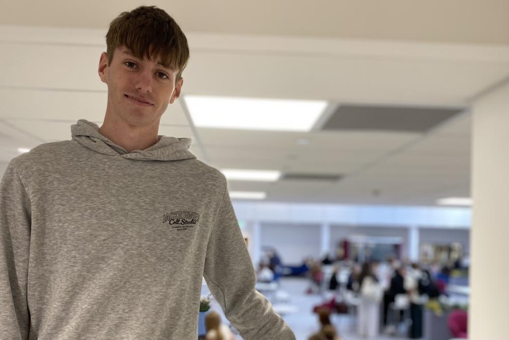 Student in grey hoodie standing in college area