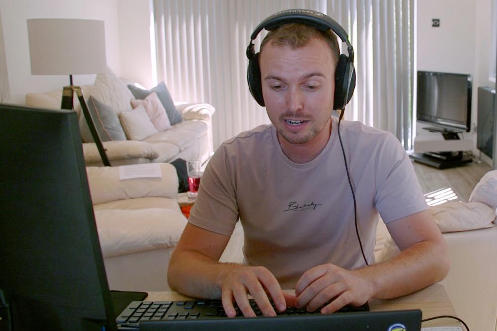 Dyn yn gweithio ar gyfrifiadur gyda chlustffonau / Man on PC with headphones