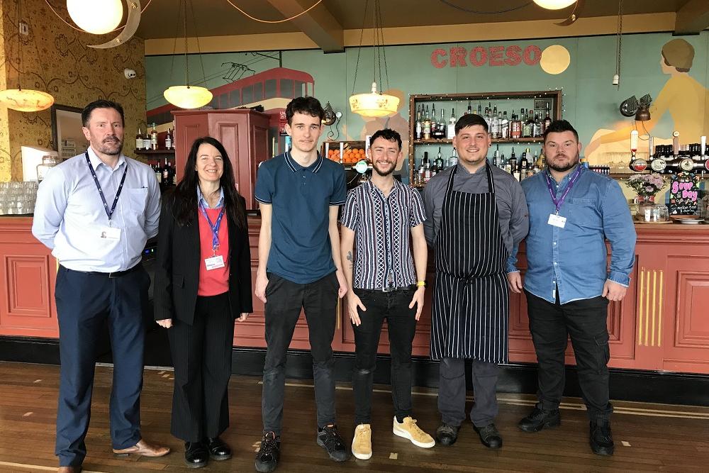 College staff, student and manager at Croeso Lounge, Mumble. Matthew Jones (Assistant Learning Area Manager), Angela Smith (ILS Tutor/Assessor), Ethan Scott, Dan Kristof (Manager, Croeso Lounge), Head Chef, Ryan Bath (ILS job coach). 
