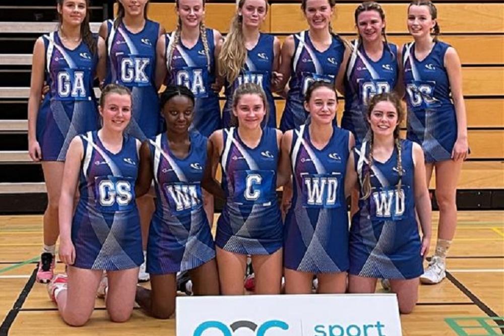 Gower College Swansea's netball team with the AOC sport sign. 