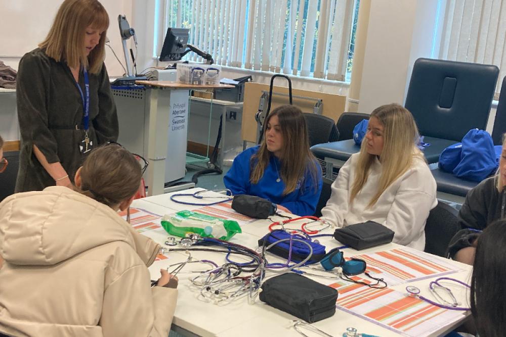 Learners sitting at table learning midwifery with dolls