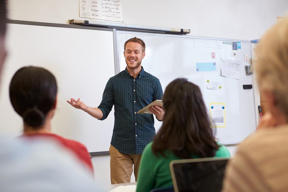  A male teacher standing in front of adult learners in a classroom